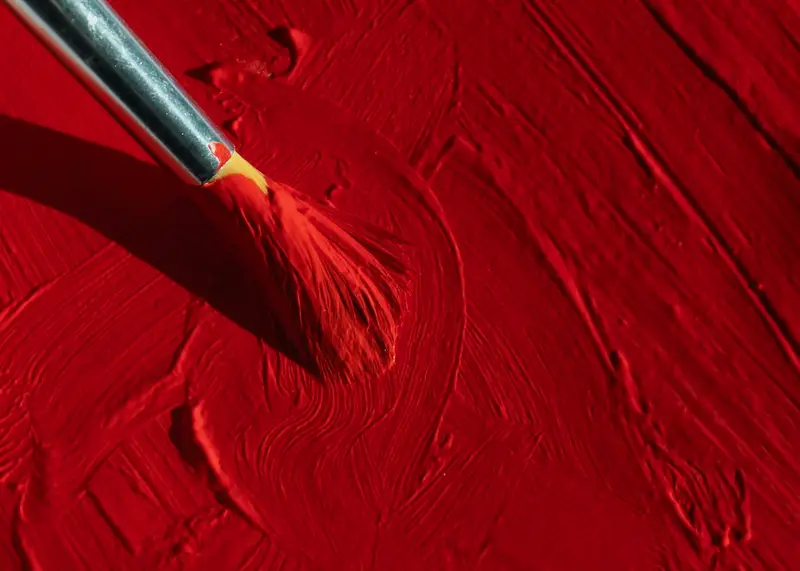Ein Pinsel zieht dicke rote Farbe über eine Fläche